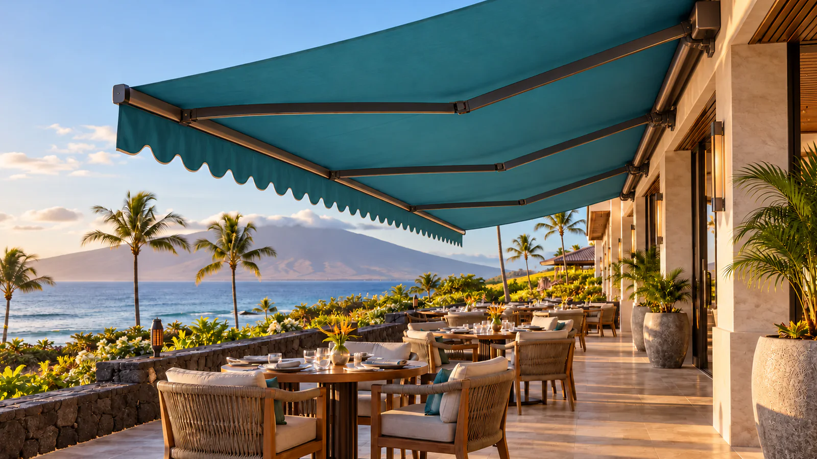 Custom teal retractable awning shading an oceanfront resort terrace in Maui
